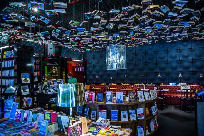 Interno di una grandiosa libreria con libri appesi al soffitto e comodi posti a sedere in un'atmosfera magica.