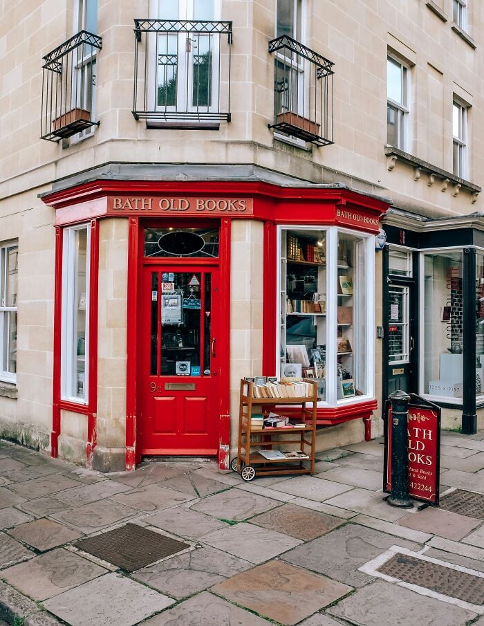Cozy and grandiose bookstore with red facade and street display, one of the magical libraries and bookstores worldwide.