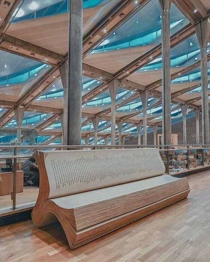 Panca a forma di libro aperto all'interno di una biblioteca moderna e grandiosa con architettura in vetro e metallo da tutto il mondo.