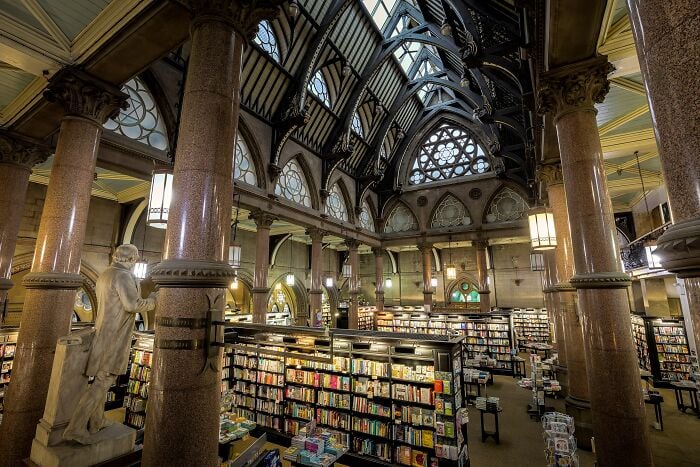 Grandiose library interior with towering columns, arched ceilings, and shelves filled with books in a magical setting.